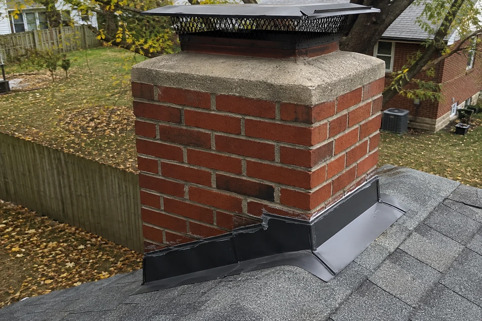 Illustration: Metal flashing along the junction of a brick chimney and shingle roof.