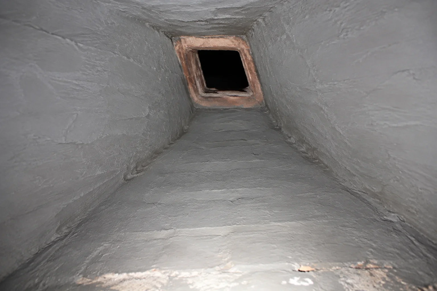 Illustration: Grey-coated tapered chamber walls leading to a terracotta flue opening.